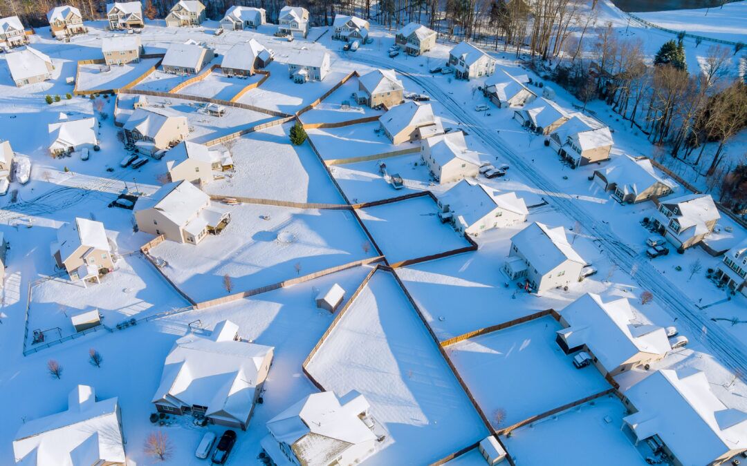 A neighborhood with snow covered roofs, leading homeowners to wonder how to maintain a roof in harsh weather conditions